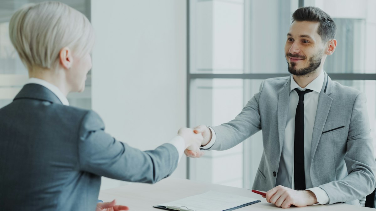 An employer and employee shaking hands after a meeting
